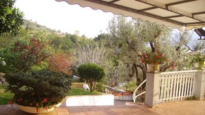 A covered patio area with a brick floor, surrounded by various plants and trees. - Camere Angela e Vincenzo (Cava de' Tirreni)