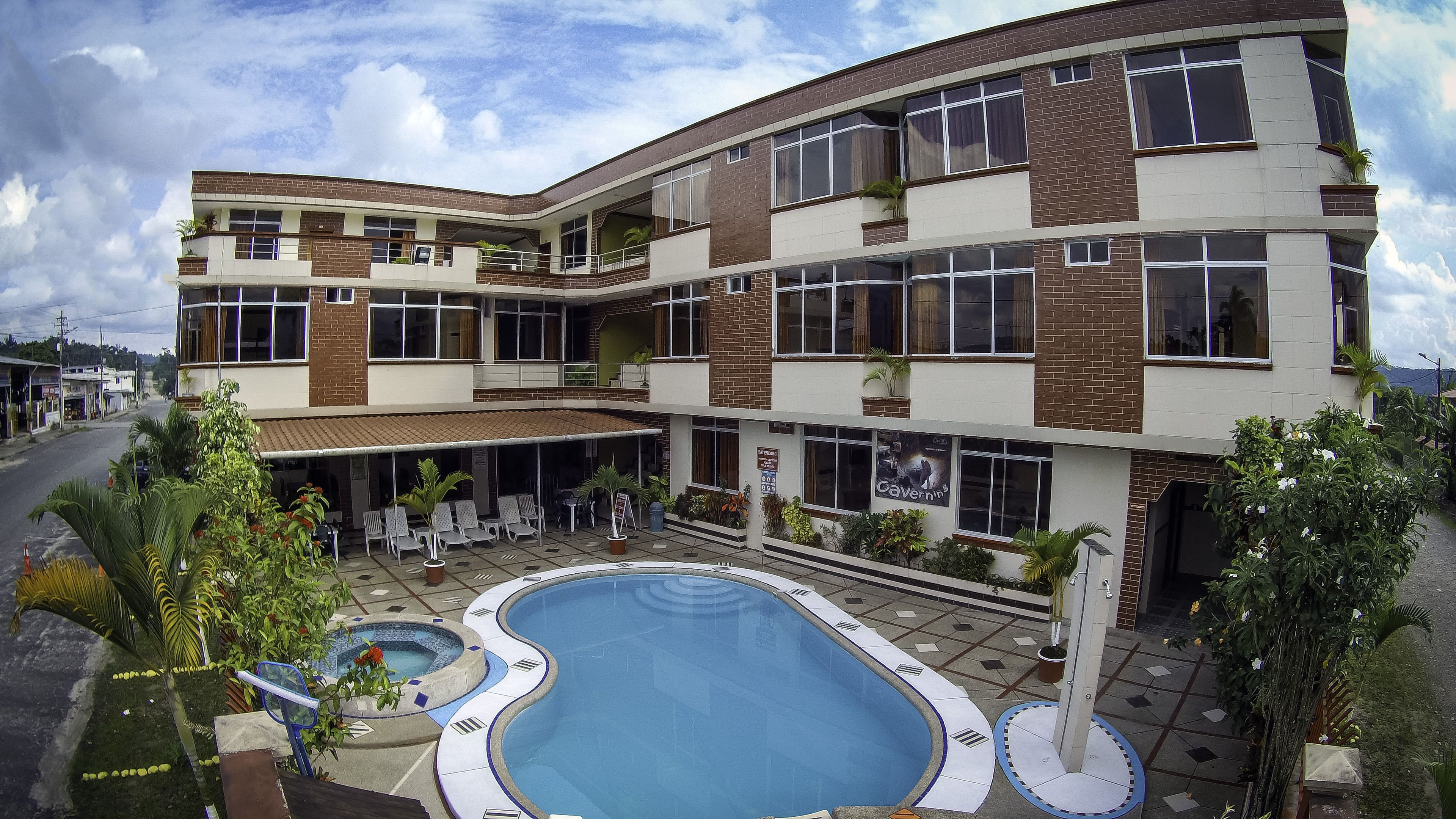 Un hotel de varios pisos con piscina, mobiliario exterior y balcones.