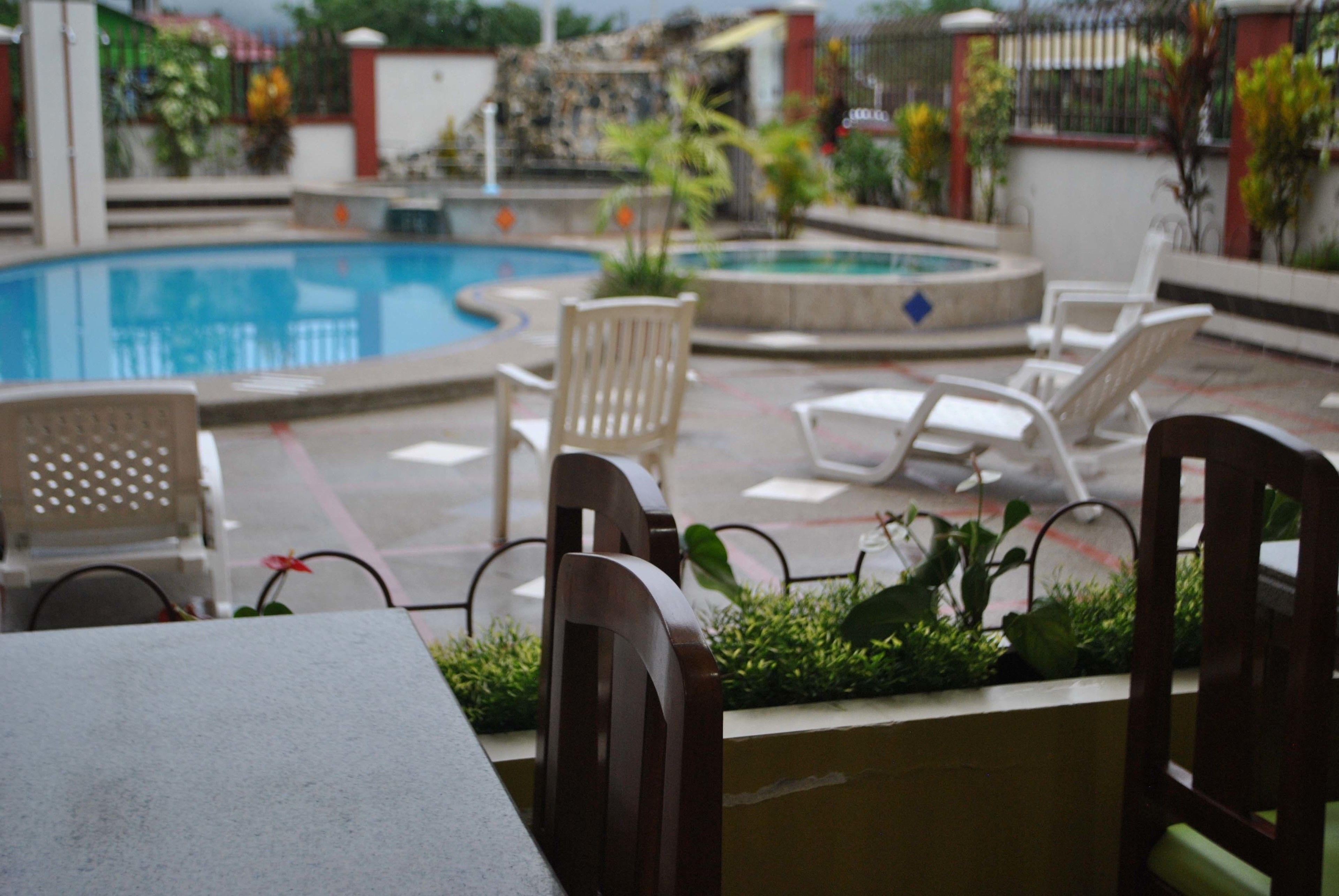 A poolside area with lounge chairs, a table, and a small garden.