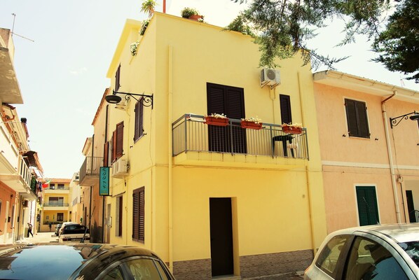 A yellow building with a balcony, a door, and a window.