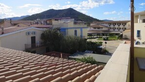 Un barrio residencial con tejados de tejas anaranjadas, un patio con pérgola y una montaña al fondo.