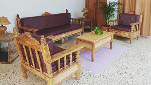 A living room with a sofa, two armchairs, a coffee table, a painting, and a potted plant. - Hotel Posada Edem (Cozumel)