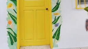 A yellow door with a number '2' above it, surrounded by a floral mural. - Hotel Posada Edem (Cozumel)
