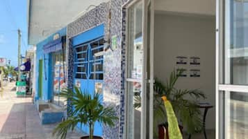 A hotel named "Hotel Edem" with a blue and white facade, potted plants outside, and a clear sky.