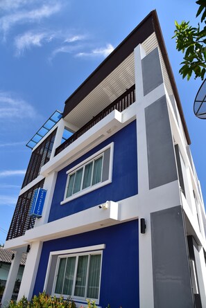 A modern two-story building with a blue facade, large windows, and a balcony.