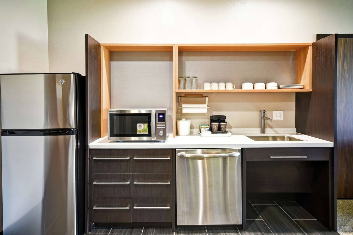 A compact kitchen with a refrigerator, microwave, coffee maker, and a sink.