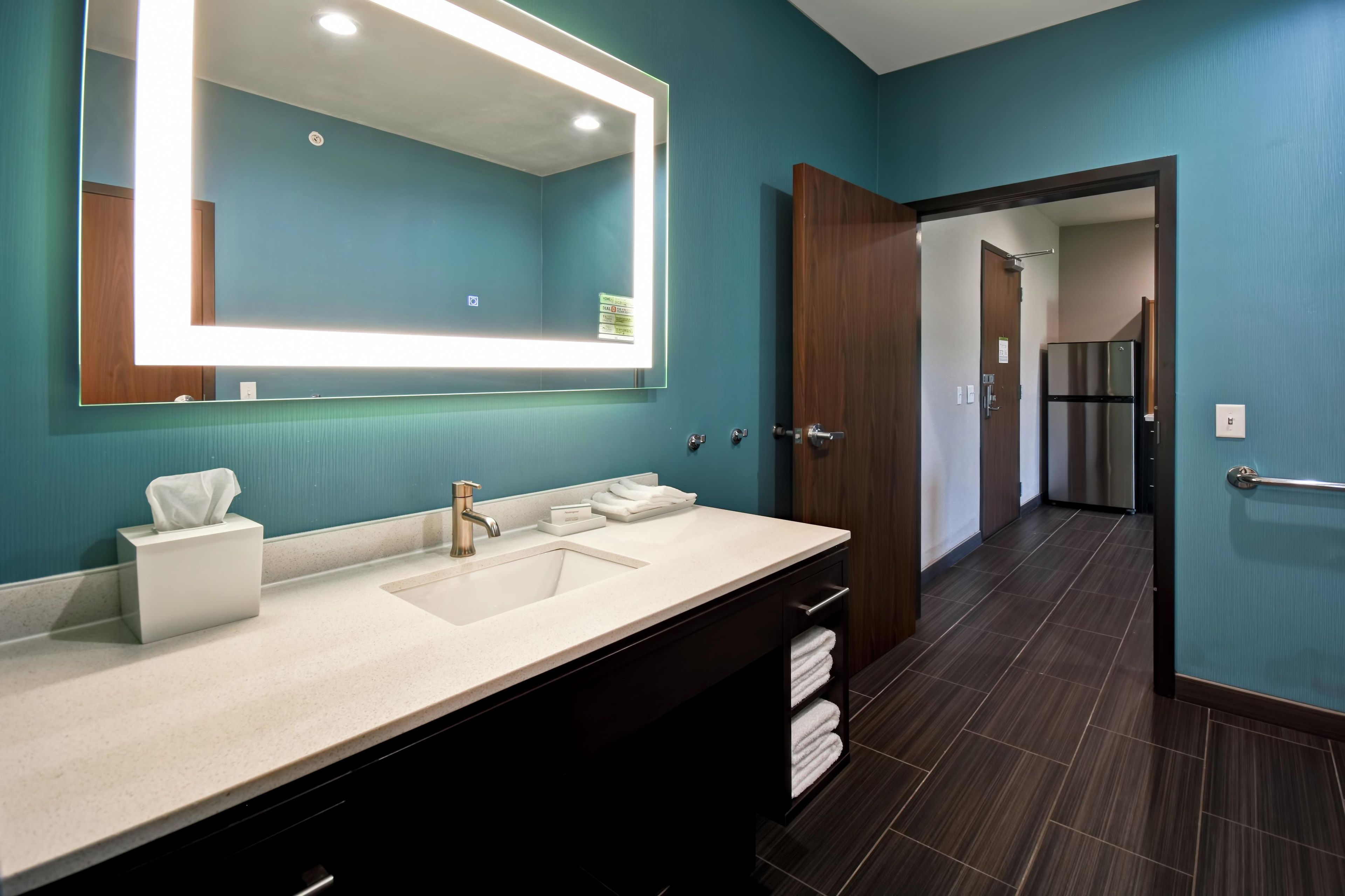 A modern bathroom with a large mirror, a sink, and a towel rack.