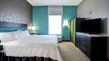 A hotel room with a bed, a flat-screen TV, a desk, and a window.