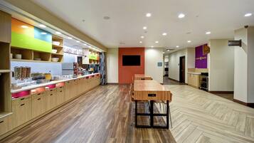 A modern restaurant with a long counter, wooden flooring, and a variety of bowls and utensils on display.