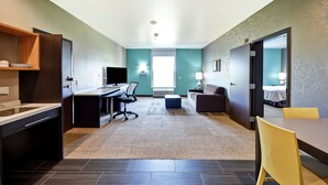 Quarto de hotel moderno com cozinha compacta, área de refeições, sofá e cama.