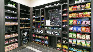 A snack and beverage kiosk with various packaged snacks and drinks, a chalkboard sign, and a welcome message.