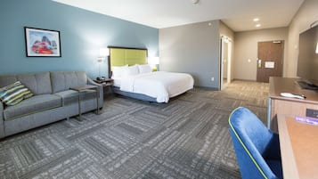 A hotel room with a bed, a sofa, a desk, and a chair.