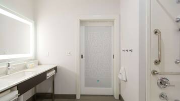 Un bagno moderno con lavandino bianco, specchio e zona doccia.