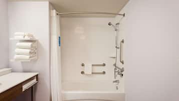 A modern bathroom with a bathtub, a toilet, and a sink. There are towels on a shelf and a shower curtain.