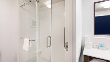 Une salle de bain moderne avec une douche à parois de verre, un lavabo blanc et un miroir au-dessus du lavabo.