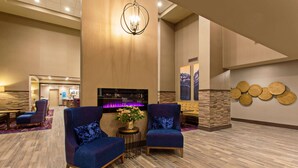 A lobby with two blue armchairs, a small table with a vase of flowers, and a chandelier. - Hampton Inn & Suites Leavenworth (Leavenworth)