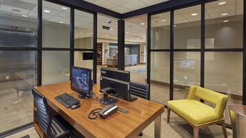 An office space with a desk, computer monitors, a telephone, and a yellow chair.