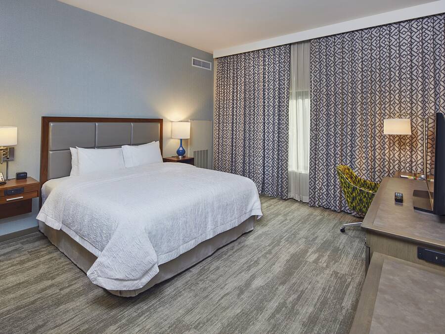 A hotel room with a large bed, bedside tables, a desk, and a chair.