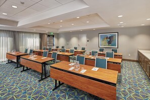 A conference room with multiple tables and chairs, a patterned carpet, and a painting on the wall. - Hampton Inn & Suites Sacramento at Csus (Sacramento)