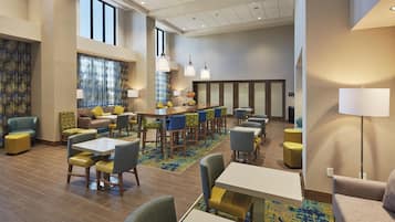 Eine Hotelhalle mit Sitzgelegenheiten, Tischen und einer Bar.