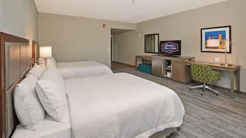 A hotel room with a double bed, a desk with a television, a chair, and a framed picture on the wall.