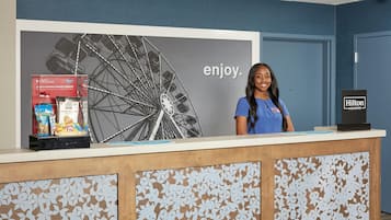 Una recepción de hotel con una imagen de una noria grande y la palabra 'enjoy' al fondo.