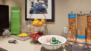 A breakfast bar with fruit bowls, cereal dispensers, and a water pitcher.
