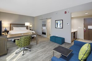 A hotel room with a bed, desk, chair, and a small seating area. - Hampton Inn & Suites Sacramento at Csus (Sacramento)