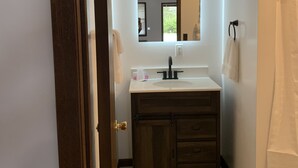 A bathroom with a white sink, dark wooden vanity, and a mirror above the sink. - Big South Fork Lodge (Jamestown)