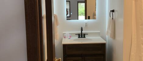 Une salle de bain avec un lavabo blanc, un meuble-lavabo en bois foncé et un miroir au-dessus du lavabo.
