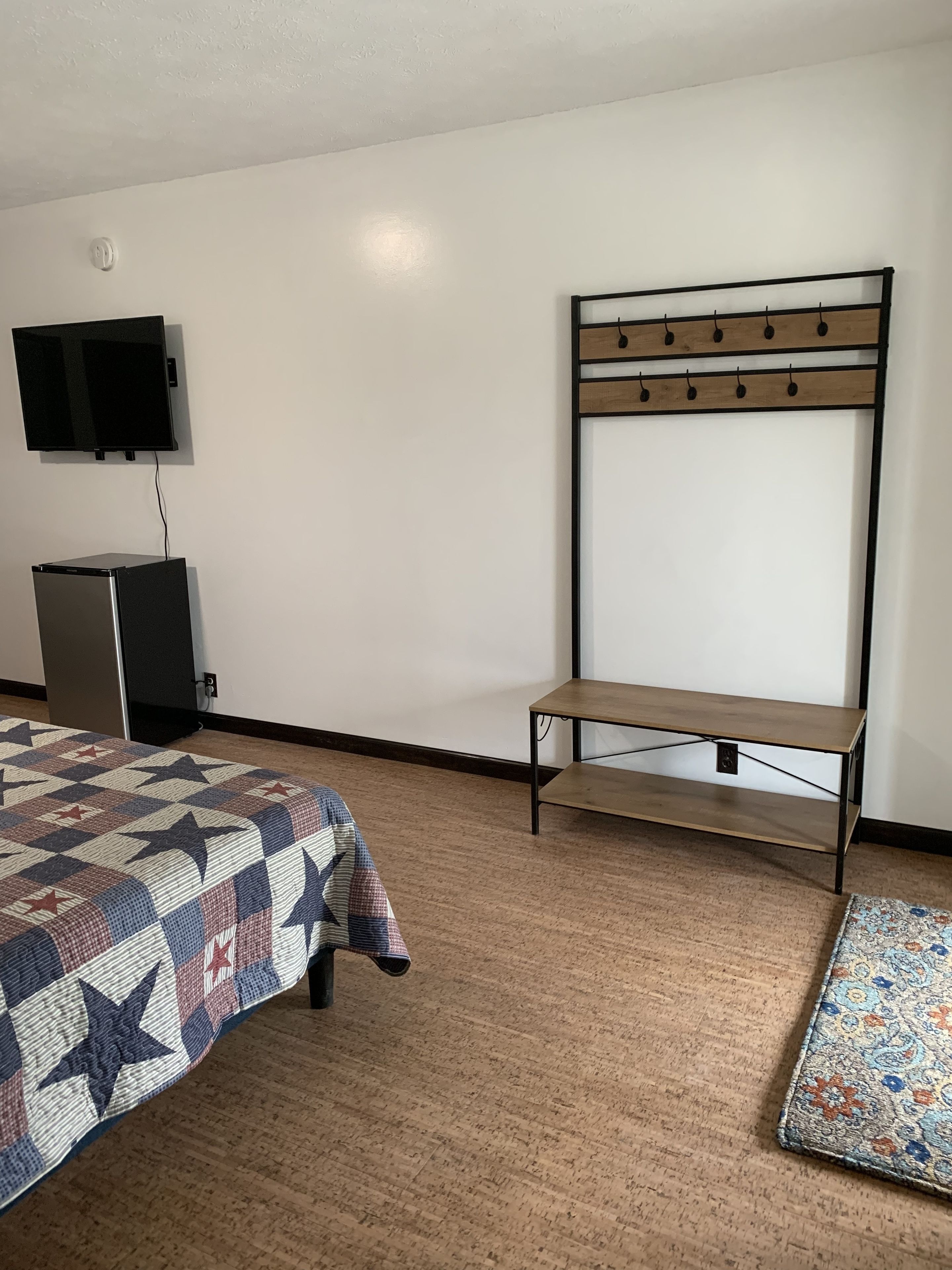 Habitación de hotel con cama, televisión, un escritorio pequeño y piso alfombrado.
