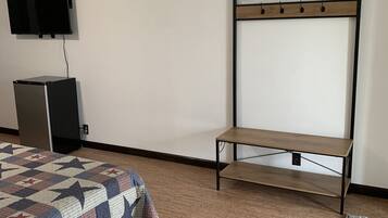 Habitación de hotel con cama, televisión, un escritorio pequeño y piso alfombrado.