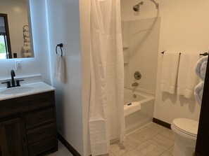 A bathroom with a sink, mirror, towel rack, shower, and toilet. - Big South Fork Lodge (Jamestown)