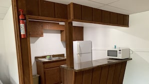 A compact kitchen with wooden cabinets, a white refrigerator, a microwave, and a sink. - Big South Fork Lodge (Jamestown)