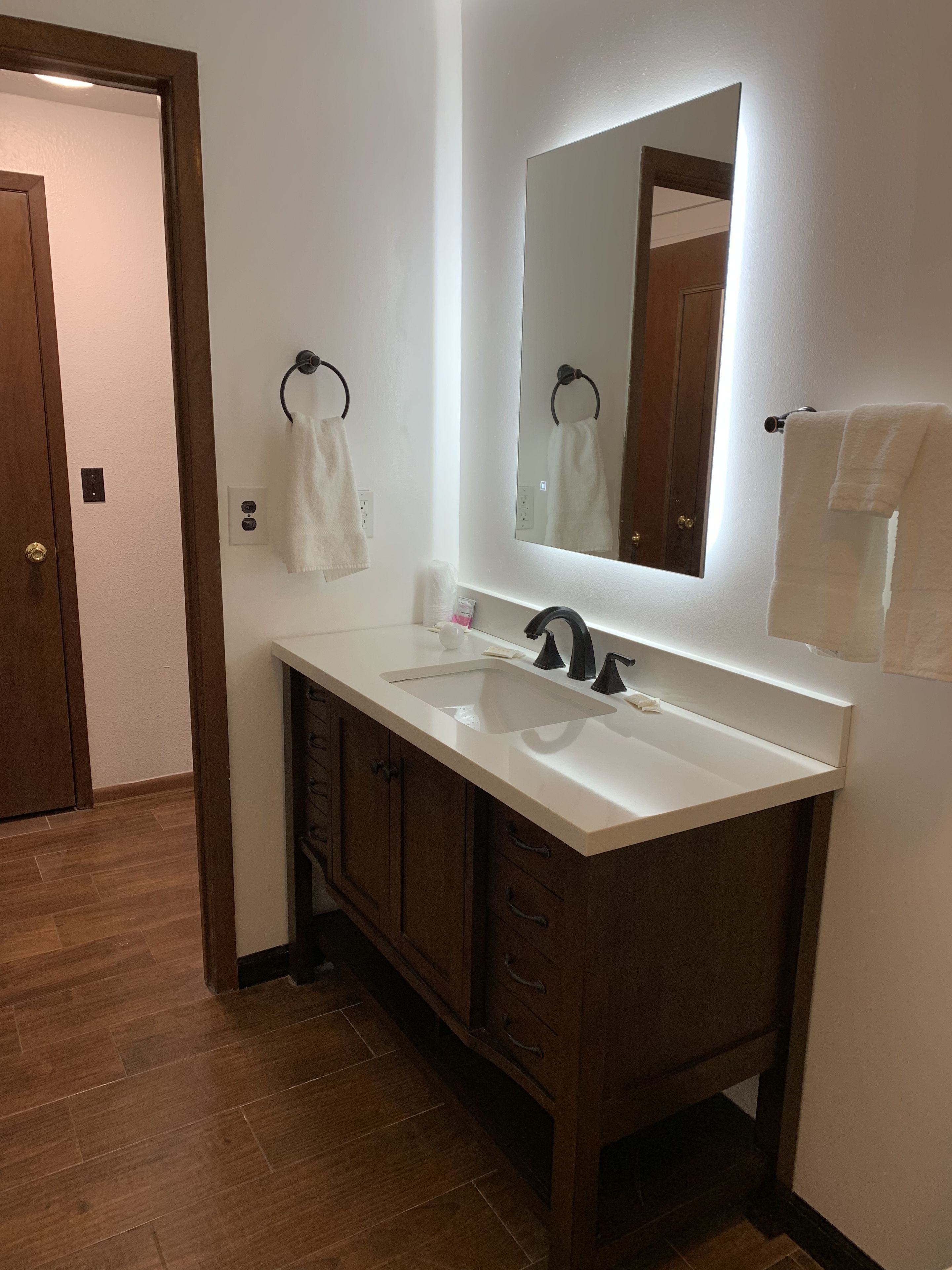 A bathroom with a white sink, dark wooden cabinets, and a large mirror.