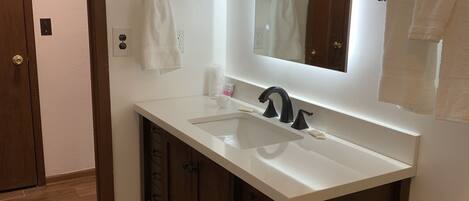 A bathroom with a white sink, dark wooden cabinets, and a large mirror.