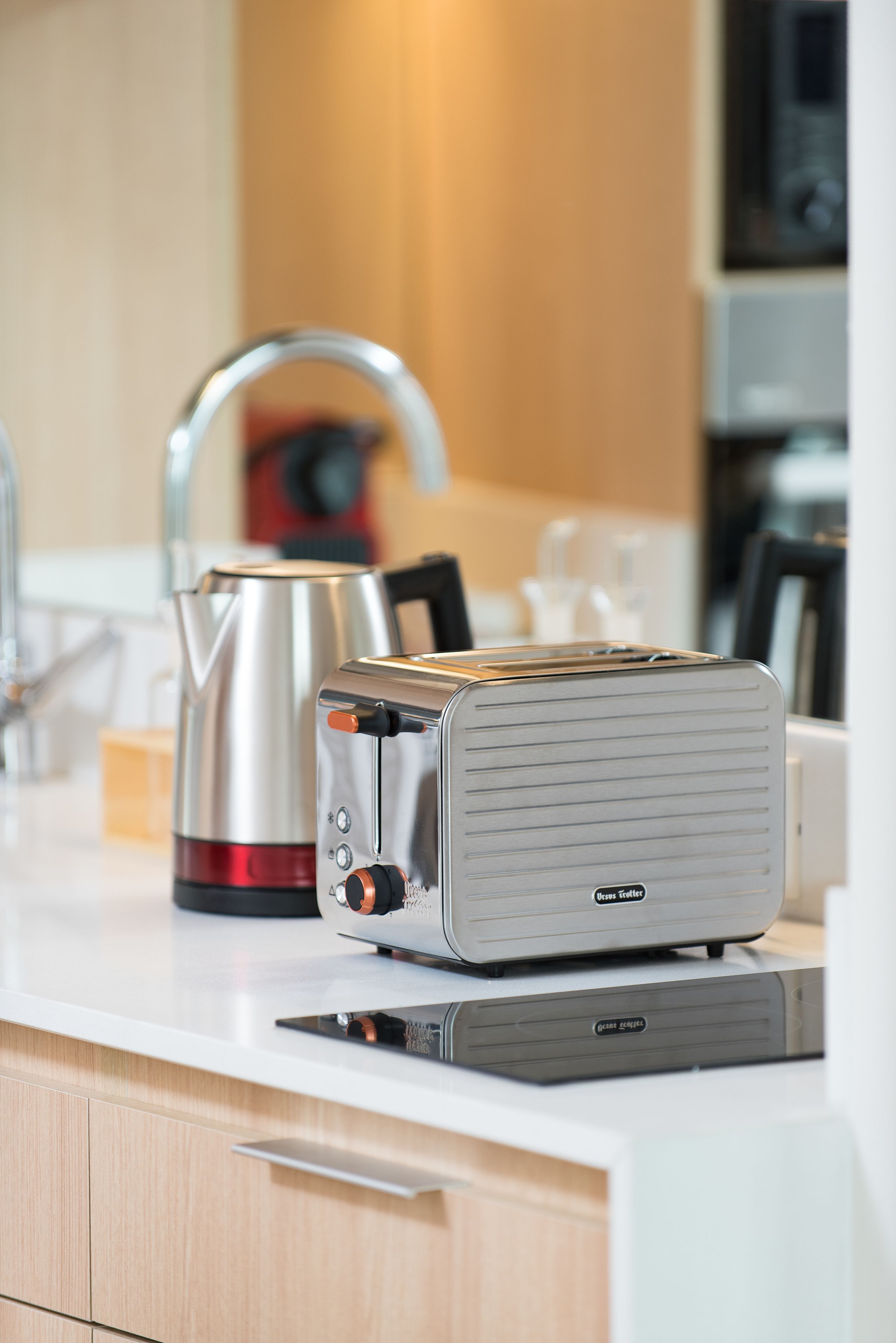 Une cuisine équipée d’un grille-pain, d’une bouilloire et d’appareils électroménagers modernes, le tout posé sur un plan de travail blanc.