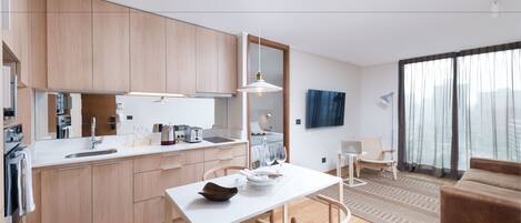 Una cocina moderna con armarios de madera, encimera blanca y comedor con mesa y sillas.