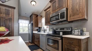 Una cocina con armarios de madera, electrodomésticos de acero inoxidable y encimera blanca.