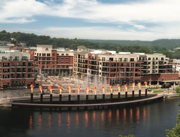 A waterfront promenade with a fountain, surrounded by multi-story buildings.