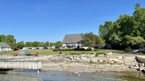 Une propriété au bord du lac, dotée d’un quai, d’une pelouse et d’une maison avec une grande terrasse.