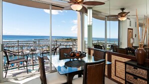 A balcony with a view of the ocean, a table with chairs, and a ceiling fan. - Absolutely Oceanfront - Amazing view- Full Kitchen- full disability access. (honolulu)