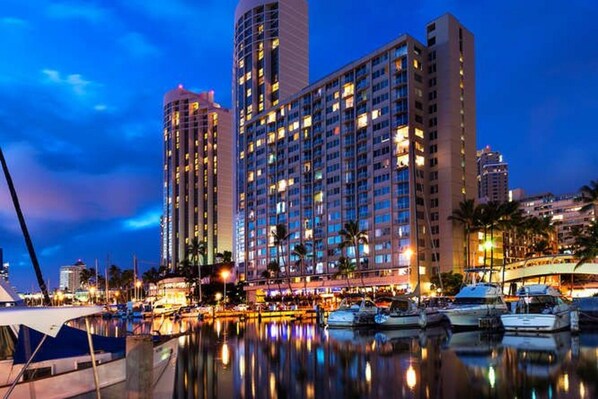 Stunning high-rise hotel with a prominent central tower overlooking a marina with docked boats.