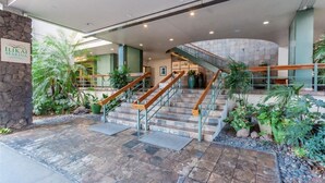 A hotel entrance with a stone wall, a sign reading "ILIKAI MARINA", a staircase with wooden handrails, and indoor plants. - Absolutely Oceanfront - Amazing view- Full Kitchen- full disability access. (honolulu)
