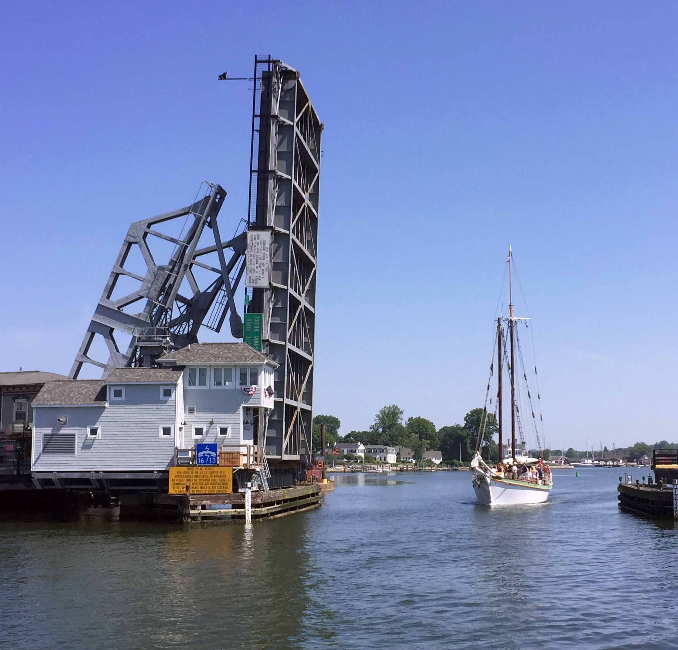 Een steiger met een grote industriële constructie en een zeilboot.