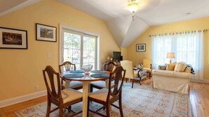 A dining area with a round table and chairs, a sofa, and a television in a living room.
