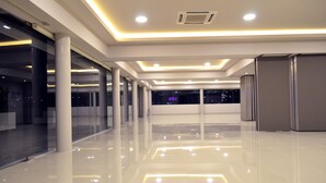 Interior espaçoso e moderno, com piso lustroso, iluminação embutida e grandes janelas com vista para o céu noturno.