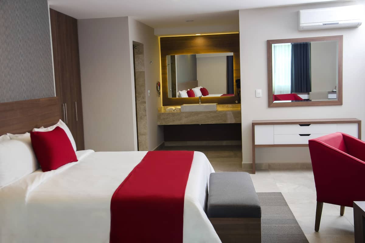 Une chambre d’hôtel équipée d’un lit, d’un bureau, d’une chaise, d’un miroir et d’un appareil de climatisation.
