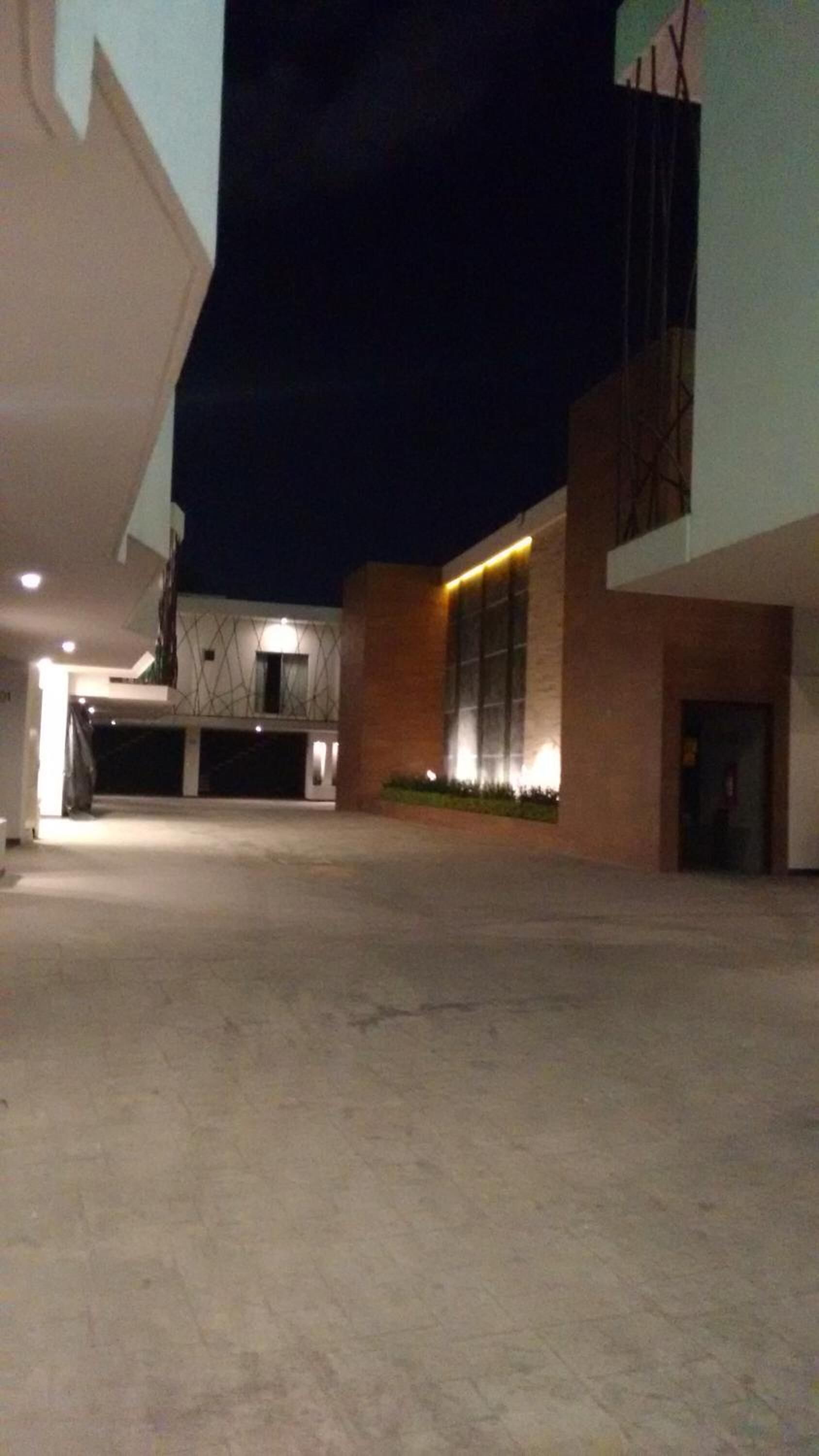 Un edificio moderno con estacionamiento techado y una entrada bien iluminada.