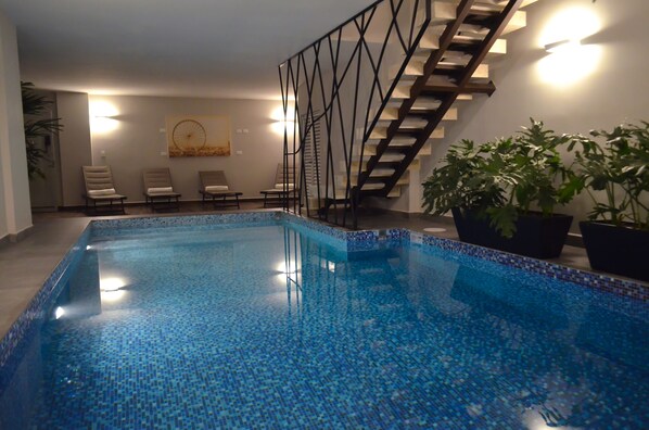 Una piscina techada, sillones reclinables de piscina